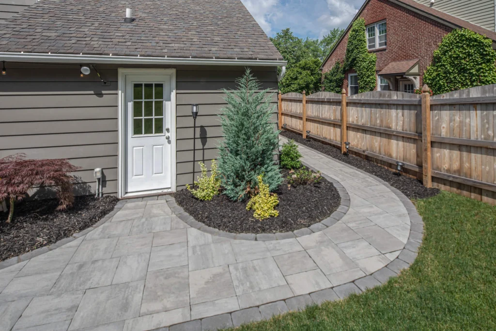 Custom patio paver installation with curved design and landscaped backyard area